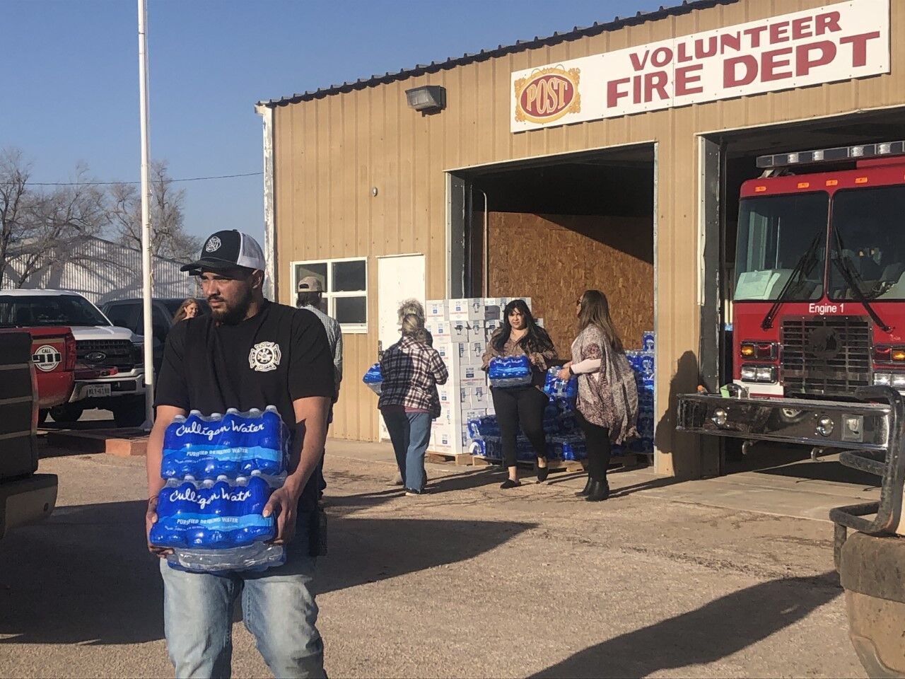 Volunteers hand out water bottles to residents in Post